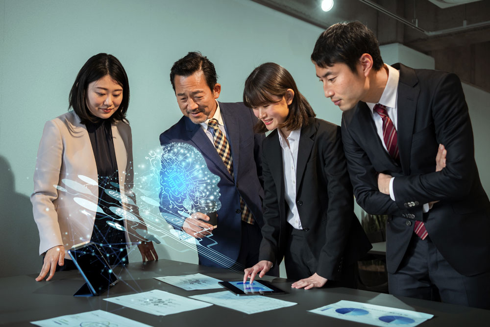 Team of Asian business professionals engaged in interactive AI technology presentation with holographic brain imagery.